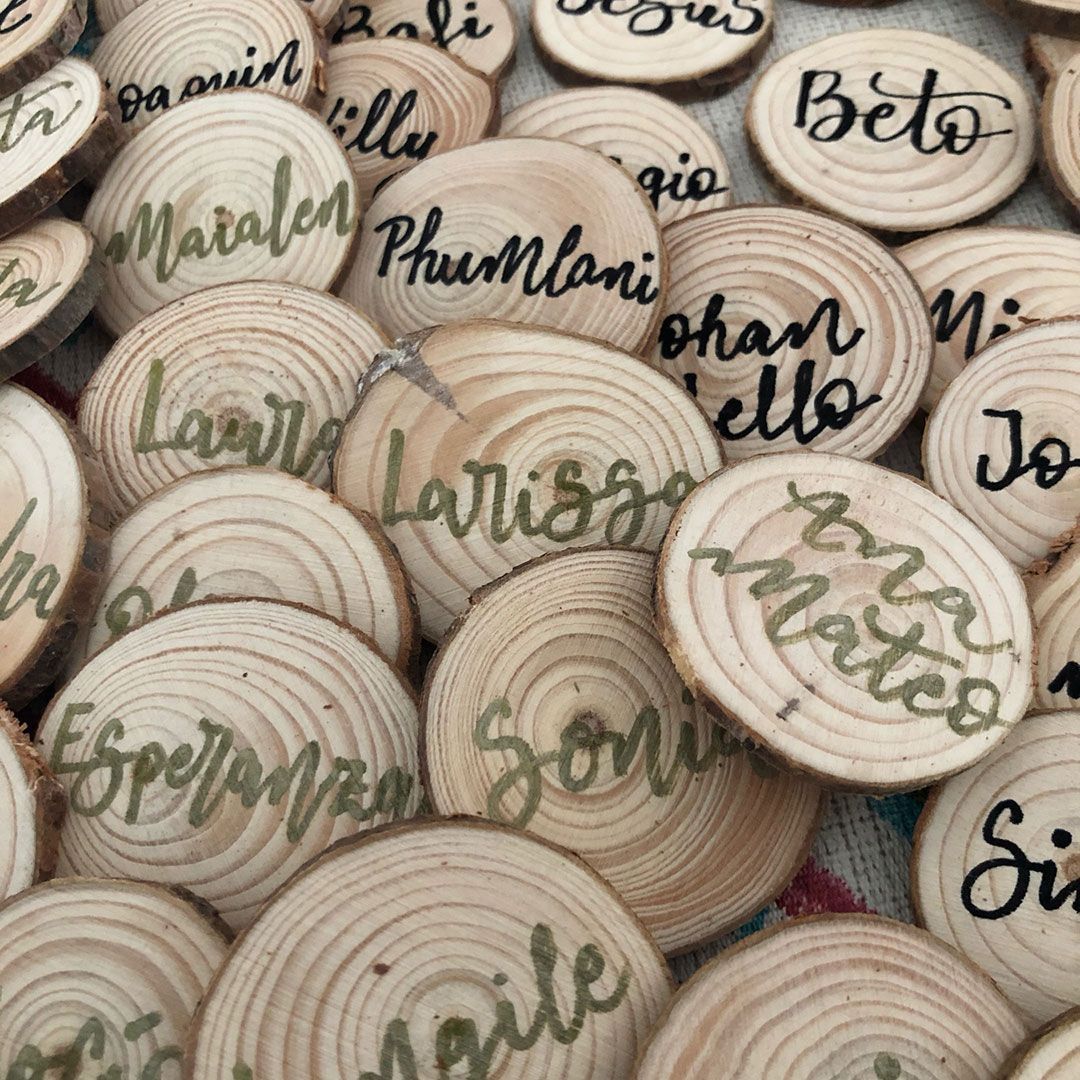 rodajas de madera con el nombre de los invitados en lettering
